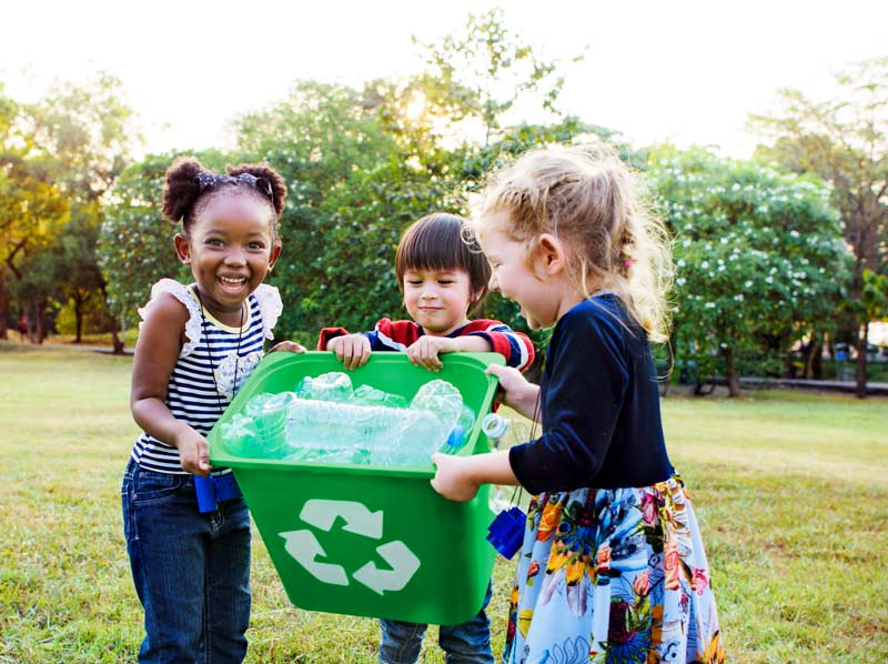 children carrying recycling bin