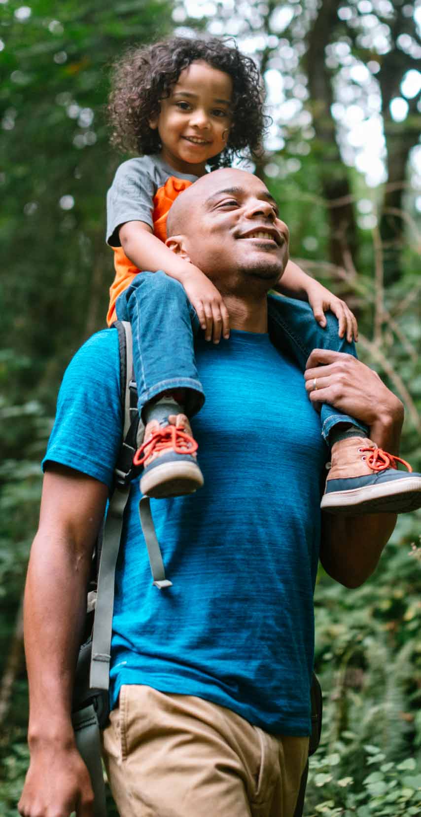 Dad hiking with daughter on shoulders