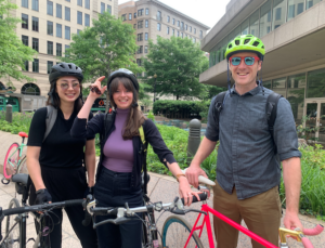 Three ecoAmerica staffers in bike helmets in front of their bikes